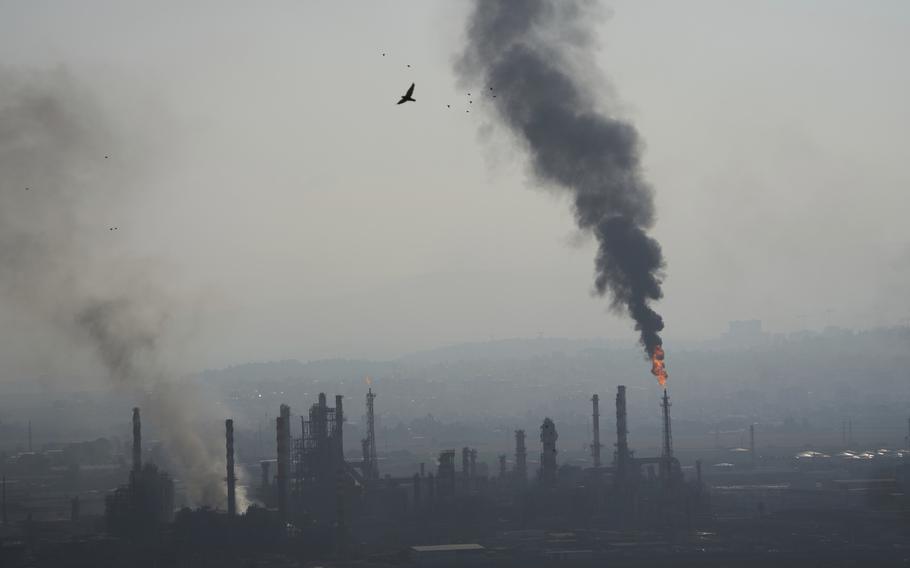 Smoke billows from an oil refinery.