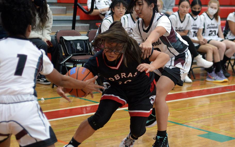 E.J. King's Angie Romero weaves between Matthew C. Perry's Ivanalis Nieves and Aiya Versoza during Saturday's DODEA-Japan basketball game. The Cobras won 56-9.