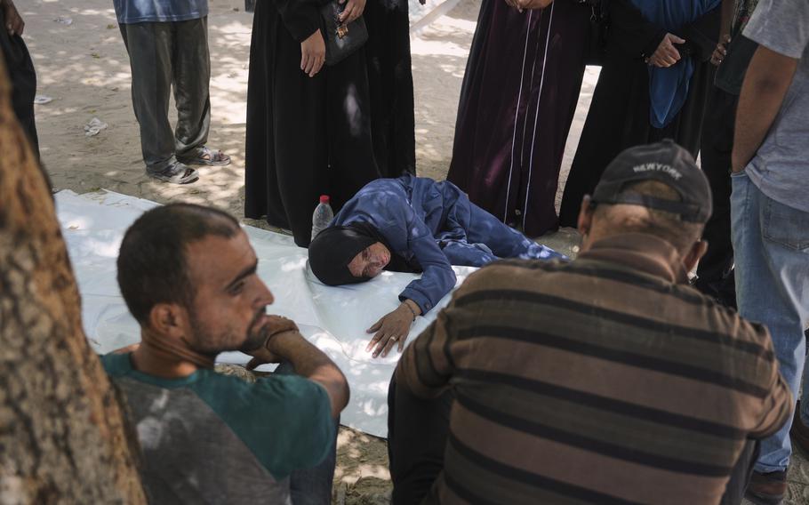 A woman lays her head on top of the casket of her son.