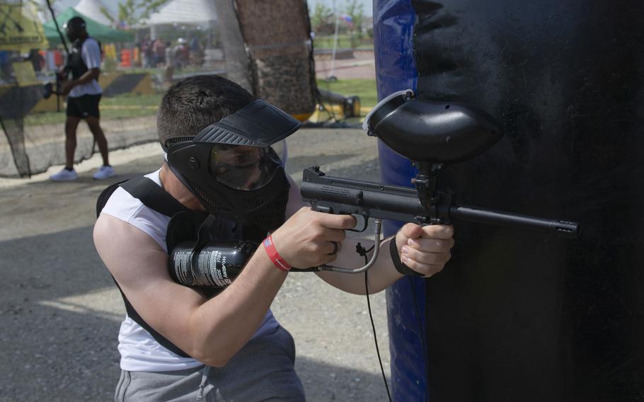 A man takes cover while playing paint ball.