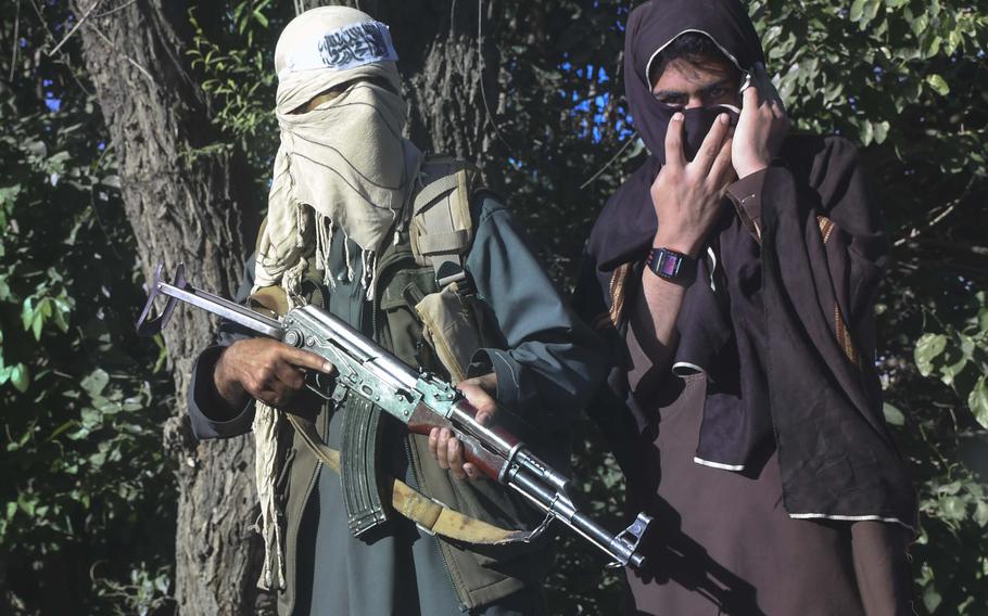 Des combattants talibans regardent un convoi de soldats de l'armée afghane passer dans la province de Logar pendant le cessez-le-feu entre les talibans et le gouvernement afghan le 16 juin 2018.