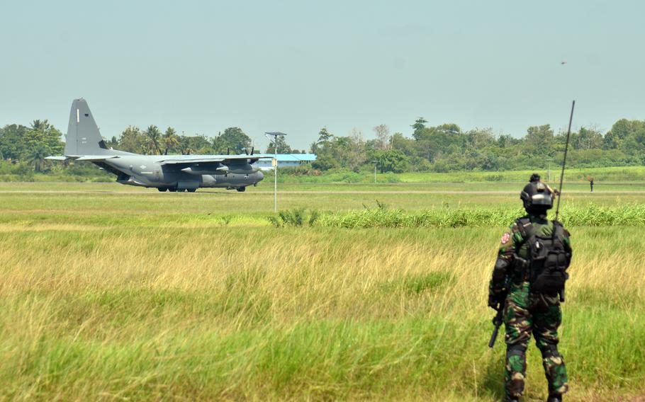 An Indonesian service member watches an MC-130J Commando II land at Sultan Mahmud Badaruddin II International Airport during Super Garuda Shield drills in Palembang, Indonesia, Tuesday, Aug. 9, 2022. 