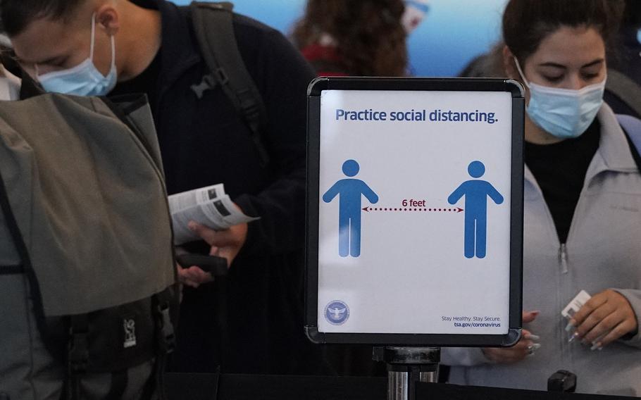 Travelers wait to check-in for their flights as a sign reminding travelers to social distance is displayed in Terminal 3 at O'Hare International Airport in Chicago, Friday, July 2, 2021. 