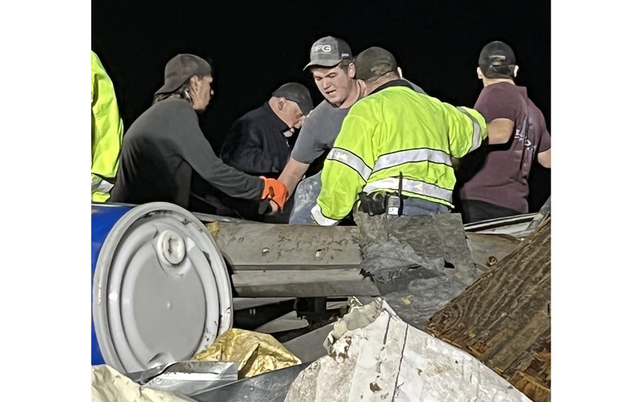 Rescuers help Alec Clark, center, from the rubble of the Mayfield Consumer Products candle factory in Mayfield, Ky. A tornado struck the facility on Dec. 10, 2021.