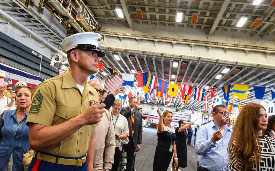 Sgt. Maj. of the Marine Corps Carlos Ruiz waves an American flag at the end of a naturalization ceremony for 60 new American citizens on Tuesday, May 7, 2024, aboard the USS Bataan. Ruiz, a native of Mexico, is a naturalized citizen. The Navy hosted the ceremony aboard the amphibious assault ship docked in the port of Miami during the city’s Fleet Week.