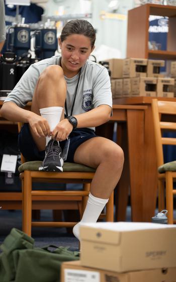 A Coast Guard Academy cadet puts on shoes