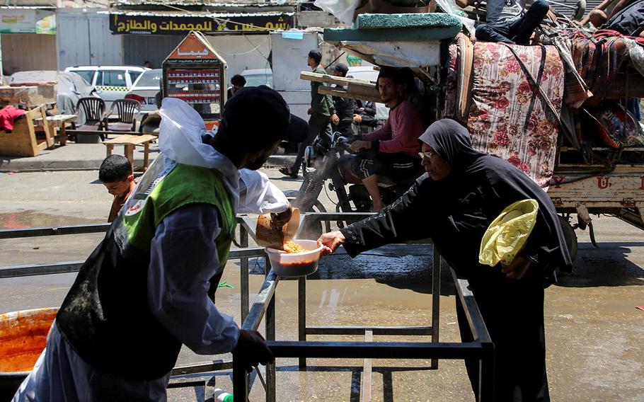 A Palestinian woman receives food from a charity kitchen in Rafah, in the southern Gaza Strip on May 8, 2024.