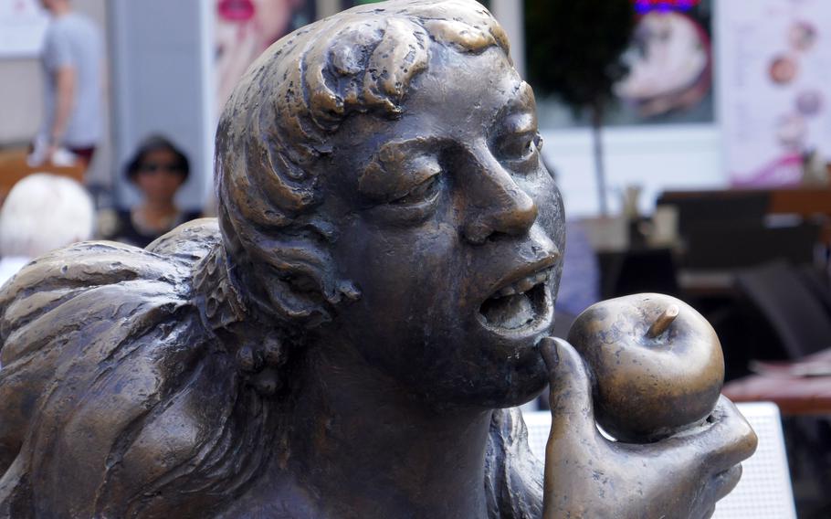 A nymph gets ready to bite into an apple, one of many figures on a playful fountain on Sternplatz in downtown Wuerzburg, Germany.