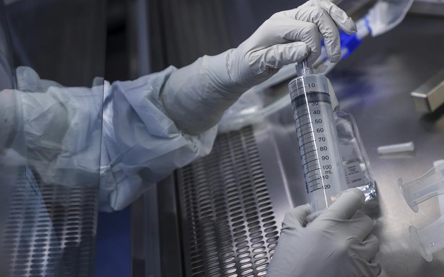 An employee prepares a syringe of raw materials for messenger RNA, the first step of COVID-19 vaccine production, at the BioNTech laboratory in Marburg, Germany, on March 27, 2021.
