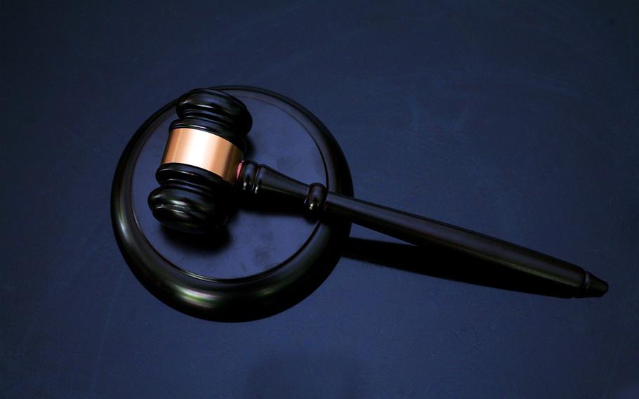 A black gavel sits against a block on a blue velvet backdrop.