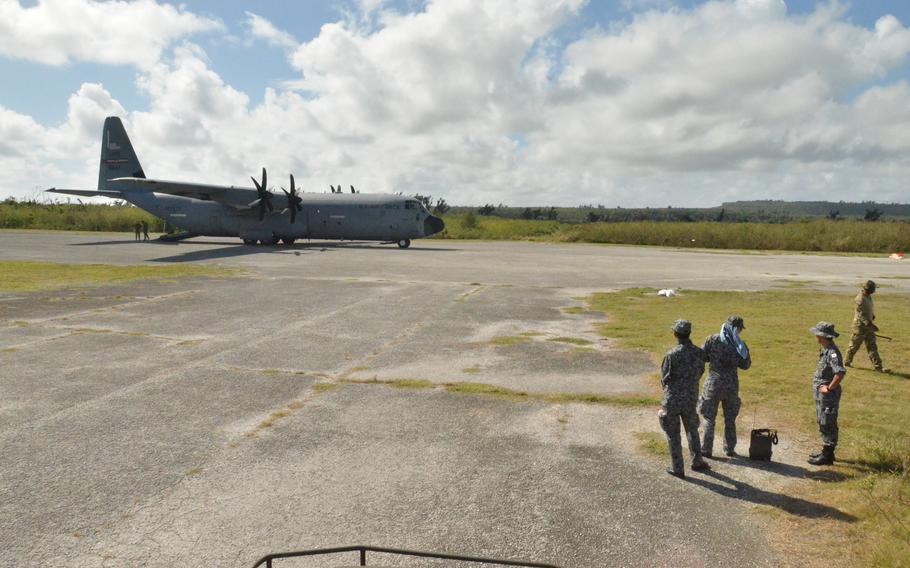 Japanese airmen watch a U.S. Air Force C-130J Super Hercules aircraft on Tinian during the COPE North airpower drills in 2020.
