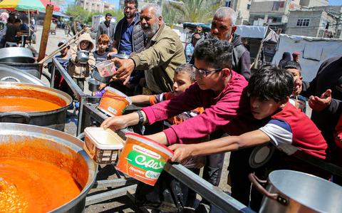 Palestinians gather to receive food from a charity kitchen in Rafah, in the southern Gaza Strip on May 8, 2024.
