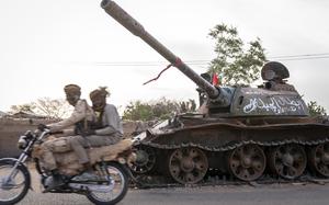 RSF soldiers on a motorbike drive by a destroyed tank belonging to the defeated Sudanese armed forces, on a main street in El Geneina, Sudan, on Feb. 20. MUST CREDIT: Diana Zeyneb Alhindawi for The Washington Post