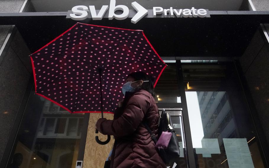 A pedestrian carries an umbrella while walking past a Silicon Valley Bank Private branch in San Francisco, Tuesday, March 14, 2023.