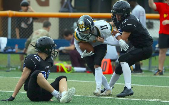 Osan's Asher Horne tries to haul down Robert D. Edgren's Hajime Reed as Osan's Dimitri Mock watches.