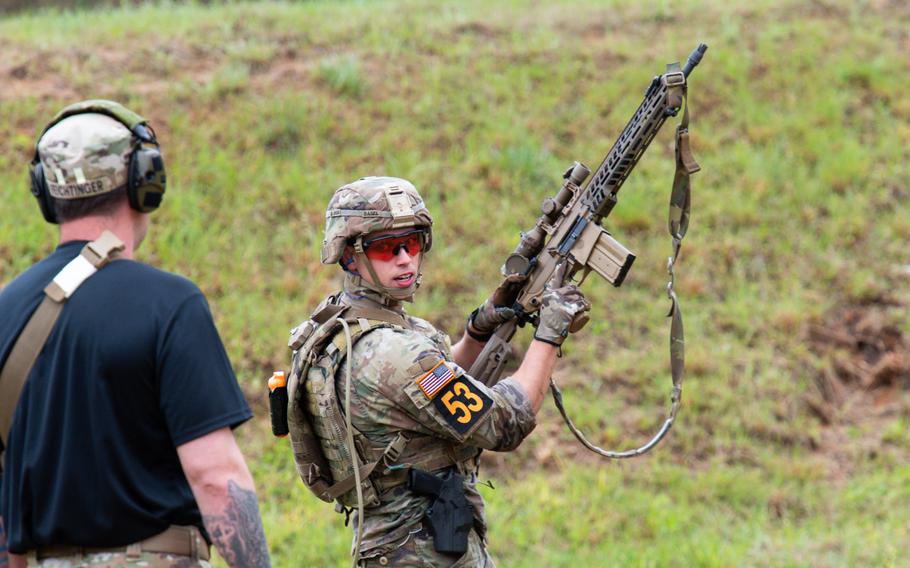 A soldier holds up an XM7 rifle 