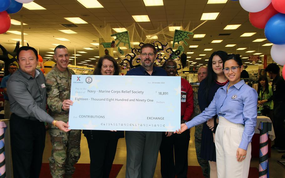David Swenson, center, general manager of Army and Air Force Exchange Service stores on Okinawa, hands over a nearly $19,000 check to Navy-Marine Corps Relief Society officials at Camp Foster, Okinawa, Oct. 20, 2023.