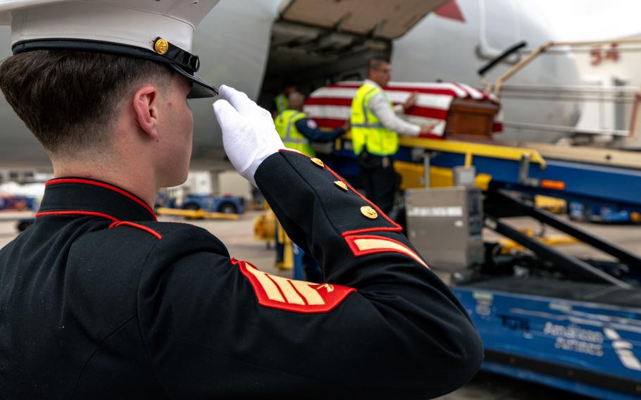 A Marine salutes a casket draped with the American flag.