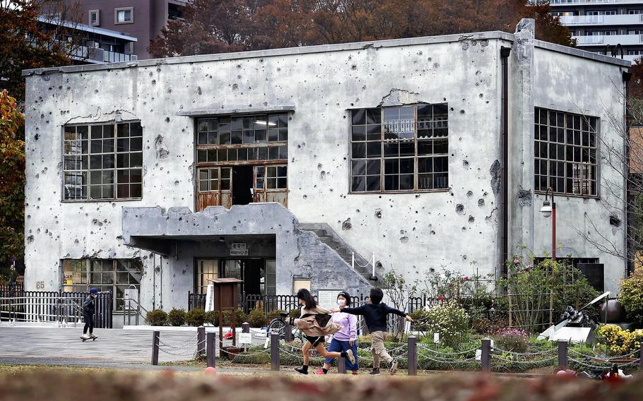 Children play in front of a former substation building with countless bullet marks at a park in Higashiyamato, Tokyo. 