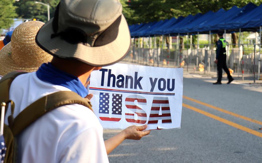 Demonstrators who support the U.S. military presence in South Korea cheer as cars exit the main gate at Camp Humphreys, South Korea, Thursday, July 27, 2023.