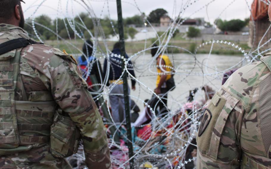 Texas National Guard soldiers block a large group of migrants from entering the U.S. from Mexico between legal ports of entry near the west Texas city of Eagle Pass. 