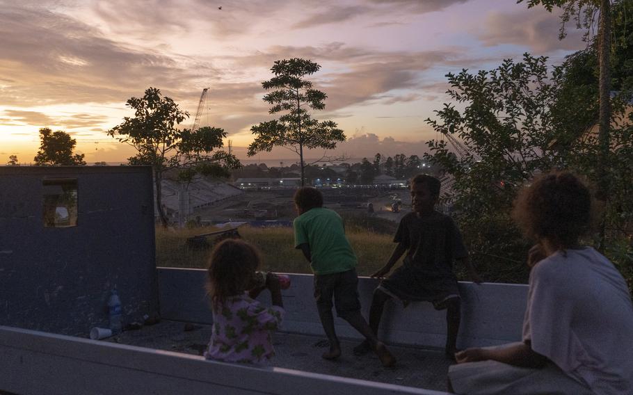 Children watch the sun set over a construction site where China is building a $50 million stadium for the Solomon Islands ahead of the 2023 Pacific Games. 