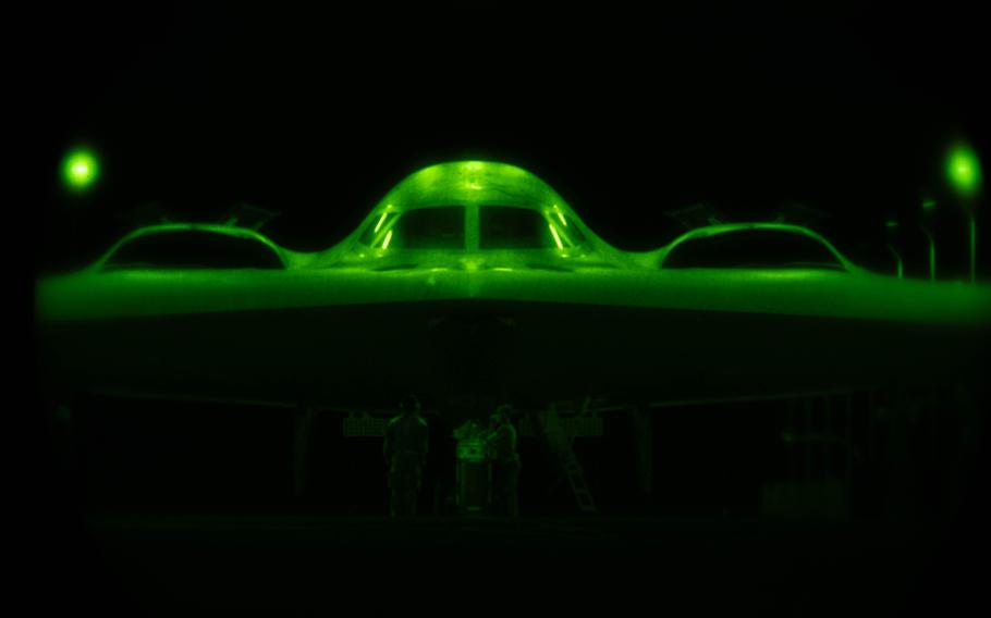 An Air Force B-2 Spirit is the dark is illuminated by green light. 