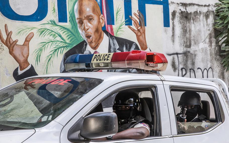 A police convoy drives past a wall painted with the president’s image down the alley of the entrance to the residence of the president in Port-au-Prince on July 15, 2021, in the wake of Haitian President Jovenel Moise’s assassination on July 7, 2021. 