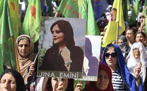 In this photo provided by Kurdish-run Hawar News Agency, Kurdish women hold portraits of Iranian Mahsa Amini, during a protest condemning her death in Iran, in the city of Qamishli, northern Syria, Sept. 26, 2022. 