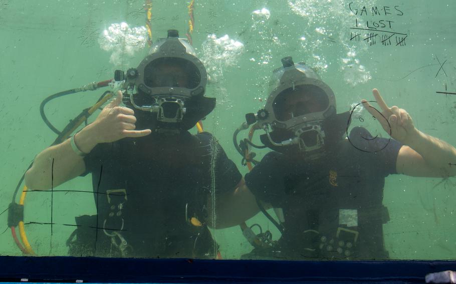Two Navy divers pose for a photo underwater