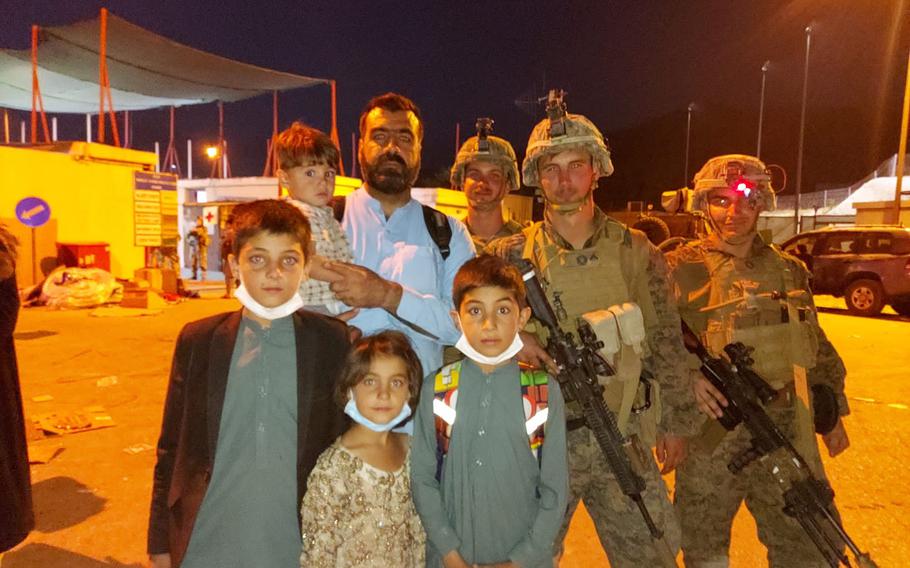 Atif Ahmadzai stands with four of his five children and U.S. Marines after he gained entry to the international airport in Afghanistan that paved the way for their trip to the United States after the fall of Kabul. They are seeking to reach New Haven, Conn.