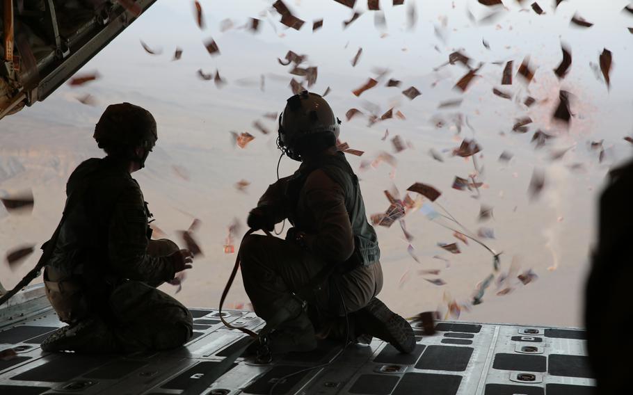 Uniformed troops drop leaflets out of an aircraft.