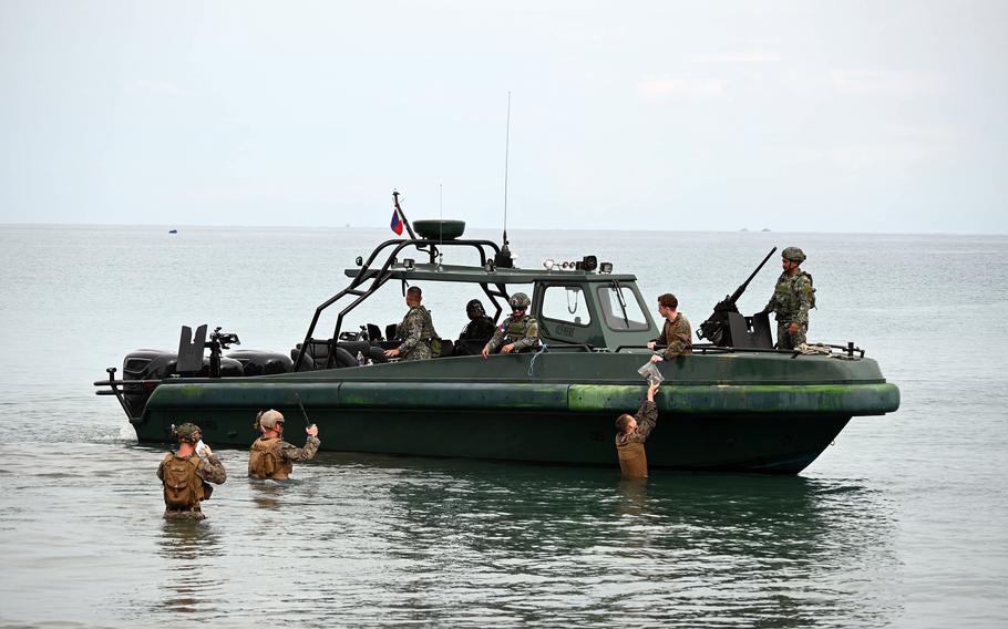 U.S. Marines wade to meet their comrades and Filipino counterparts in a small boat off the coast.