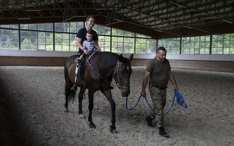 Vasyl Irkha leads Serheii, 26, during a therapeutic horseback riding lesson as Egor, 2, shares the saddle with his father on July 31, 2022.