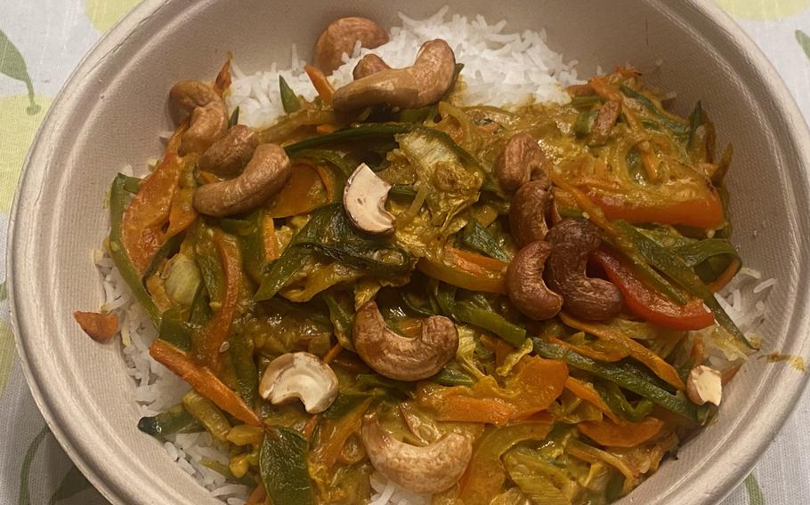Oelmuehle’s curry with rice is a vegan dish consisting of cashews, coconut, mango and assorted vegetables in a curry sauce on a bed of white rice.