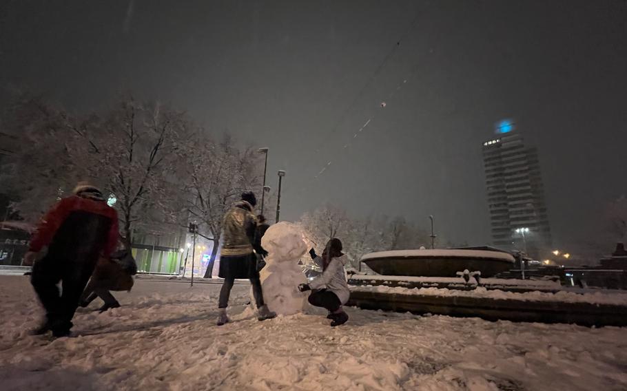 German college students build a snowman while waiting for their bus April 8, 2022, in Kaiserslautern, Germany. City buses and trains throughout the region were canceled, leaving some travelers stranded during unexpectedly severe weather.