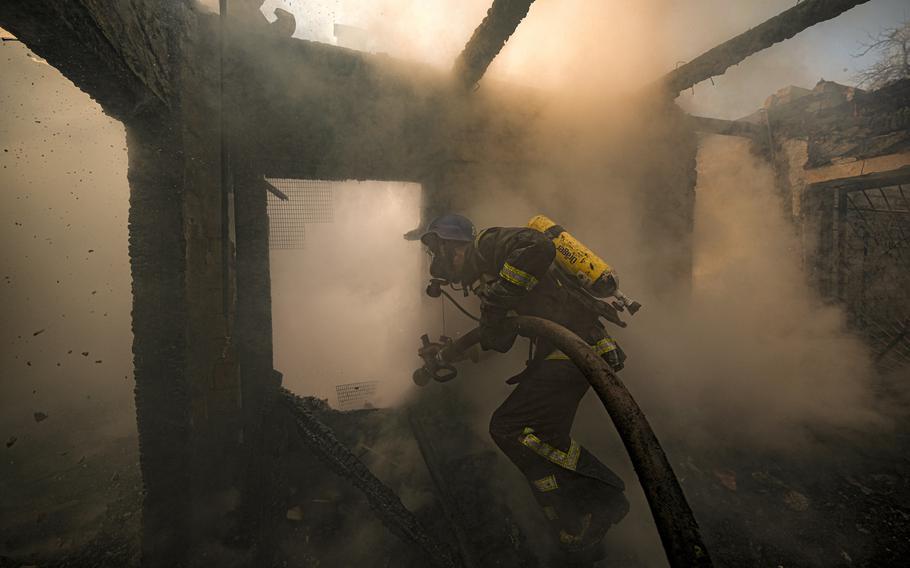 A Ukrainian firefighter sprays water inside a house destroyed by shelling in Kyiv, Ukraine, Wednesday, March 23, 2022. 