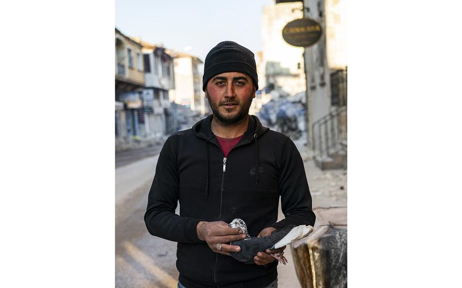 Mustafa Ugur, 27, holds one of his friend’s pigeons as they collect them on Kurtulus Street on Feb. 17, 2023.