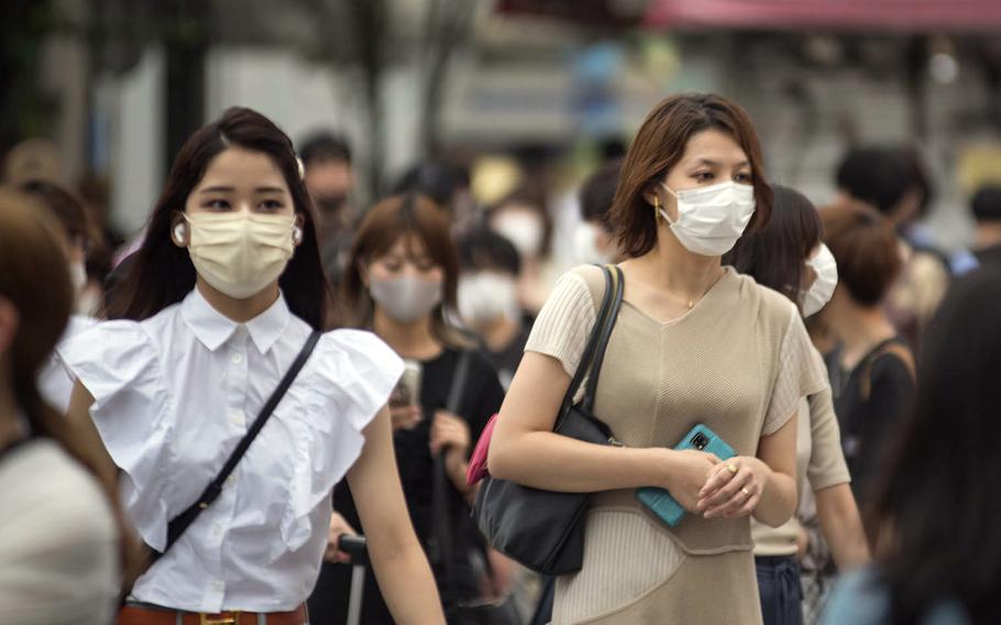 Commuters walking near Shinjuku Station wear masks to guard against the coronavirus early this summer in central Tokyo. 