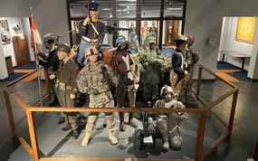 Military uniforms are on display in a museum.