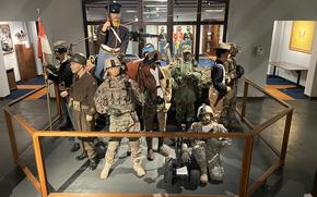 Military uniforms are on display in a museum.