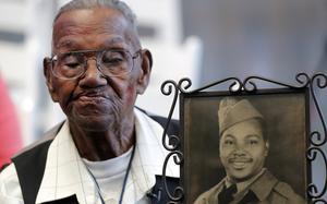 FILE - World War II veteran Lawrence Brooks holds a photo of him taken in 1943, as he celebrates his 110th birthday at the National World War II Museum in New Orleans, on Sept. 12, 2019.  Music and thoughtful tributes filled a portion of The National WWII Museum where family and friends gathered Saturday, Jan. 15, 2022, to remember Lawrence Brooks, the oldest World War II veteran who died earlier this month. Brooks, who died Jan. 5, was 112.  (AP Photo/Gerald Herbert, File)
