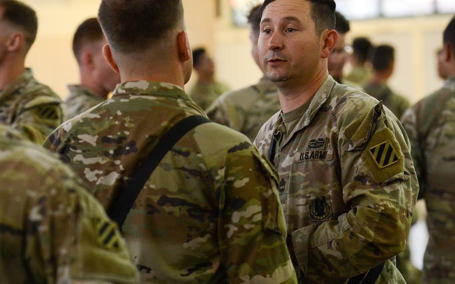 Army Sgt. 1st Class Joshua Cooner, a tank platoon sergeant with 3rd Battalion, 69th Armored Regiment, right, speaks with fellow soldiers just before boarding a flight to Germany as part of a short-notice deployment to Europe at Hunter Army Airfield, Ga., on Wednesday, March 2, 2022. The 1st Armored Brigade Combat Team, 3rd Infantry Division — including Cooner’s battalion — was ordered to Europe on a short-notice deployment after Russia invaded Ukraine.
