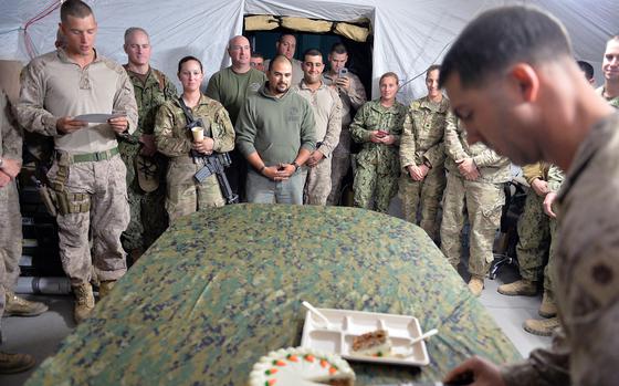 Qayara Airfield West, Iraq, Nov. 10, 2016: Cpl. David Dennis reads about the significance of the passing of the cake from the oldest to the youngest Marine as part of the traditional Marine Corps birthday celebration, as Maj. Ryan Hunt cuts a slice of carrot cake.

META TAGS: USMC; U.S. Marine Corps; celebration; birthday; 