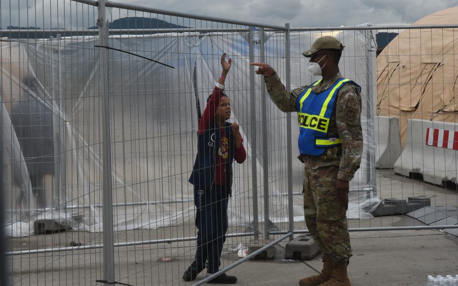 A boy talks through the fence with a security forces airman at a temporary living facility set up for evacuees from Afghanistan on Ramstein Air Base, Germany, Aug. 23, 2021.