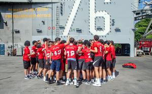 Members of the Nile C. Kinnick High School football team cheer during a visit to the aircraft carrier USS Ronald Reagan at Yokosuka Naval Base, Japan, Tuesday, Sept. 12, 2023. 