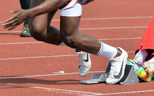 A sprinter uses the blocks for a quick start.