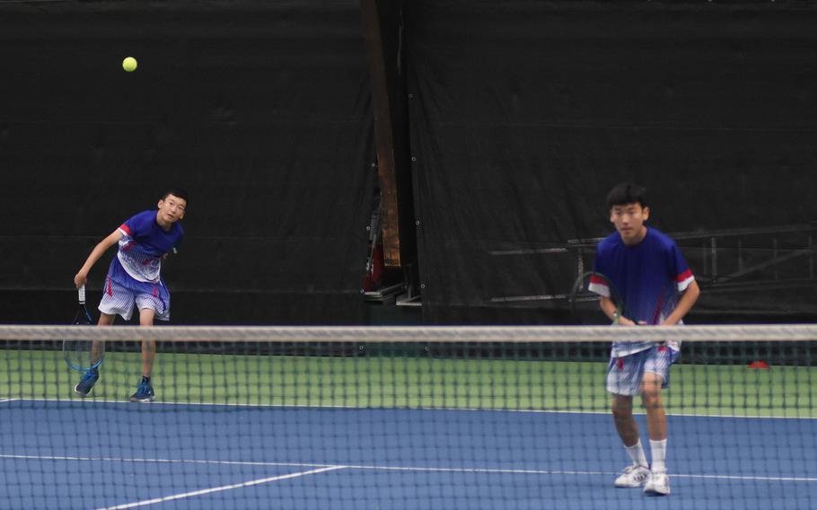 Ramstein’s Sean Kim serves the ball next to his brother and teammate, Eric Kim, during a semifinals match at the DODEA European tennis championships on Friday, Oct. 21, 2022, in Wiesbaden, Germany. 
