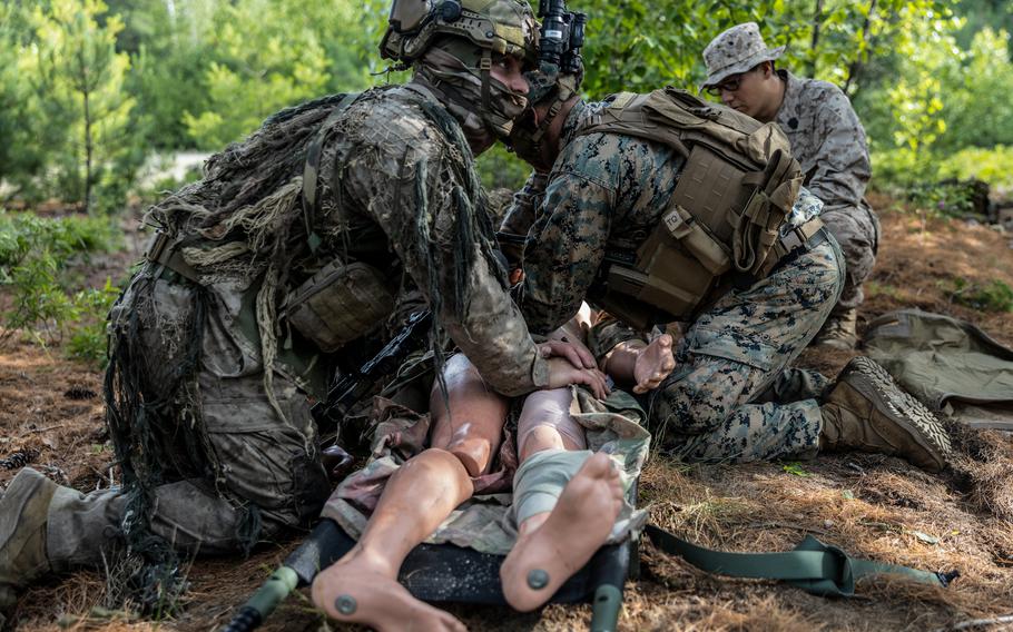 Two men secure a dummy to a stretcher.