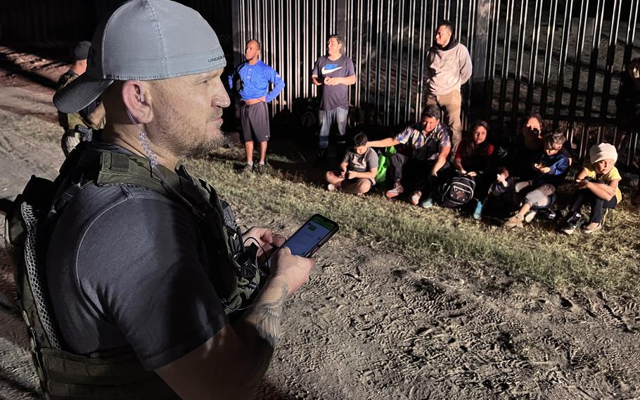 Samuel Hall, 40, North Texas-based founder of the Patriots for America militia, surveys a group of migrants stopped by U.S. Customs and Border Protection agents after crossing the Rio Grande in Eagle Pass, Texas, last month. 